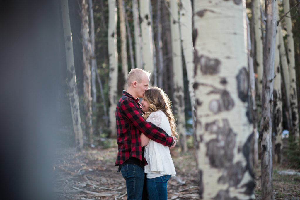 evergreen colorado engagement session in aspen grove couple snuggles and forehead kisses