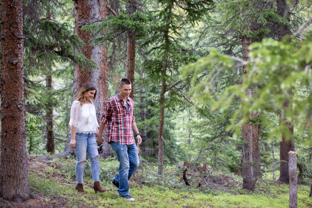 loveland pass engagement session colorado couple holds hands and walks in forest
