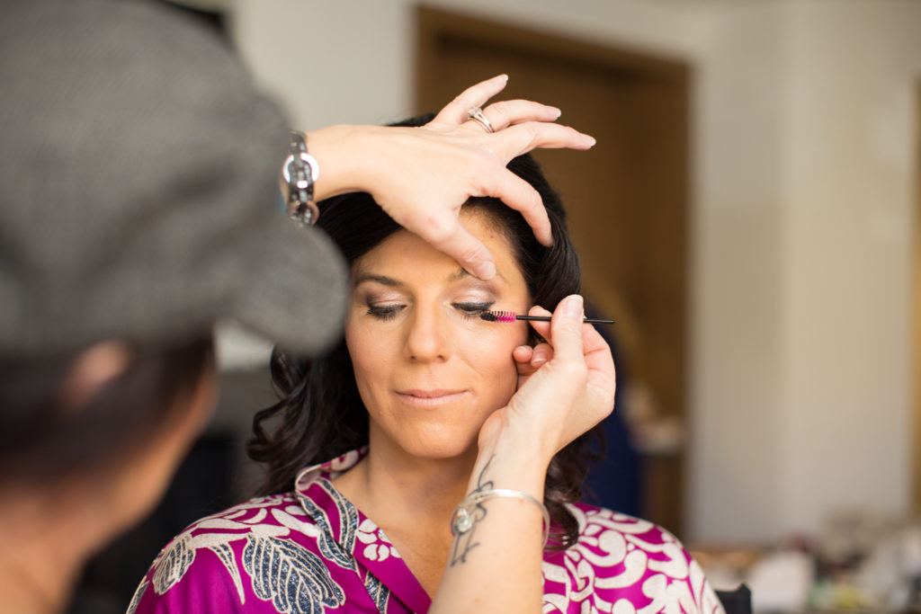 bride getting her mascara done before wedding at Little Nell in Aspen Colorado