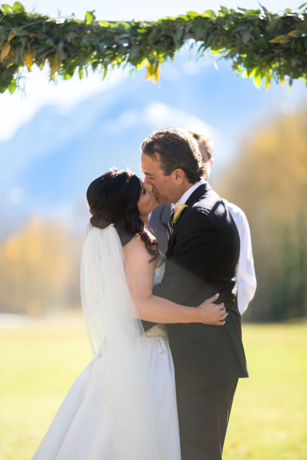 bride and groom share intimate first kiss in front of mountains during T Lazy 7 ranch wedding in Aspen Colorado