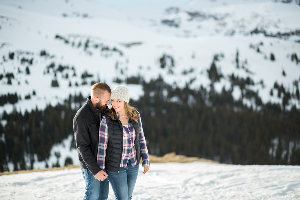 couple wears beanie and plaid for winter snowy loveland pass engagement photo session