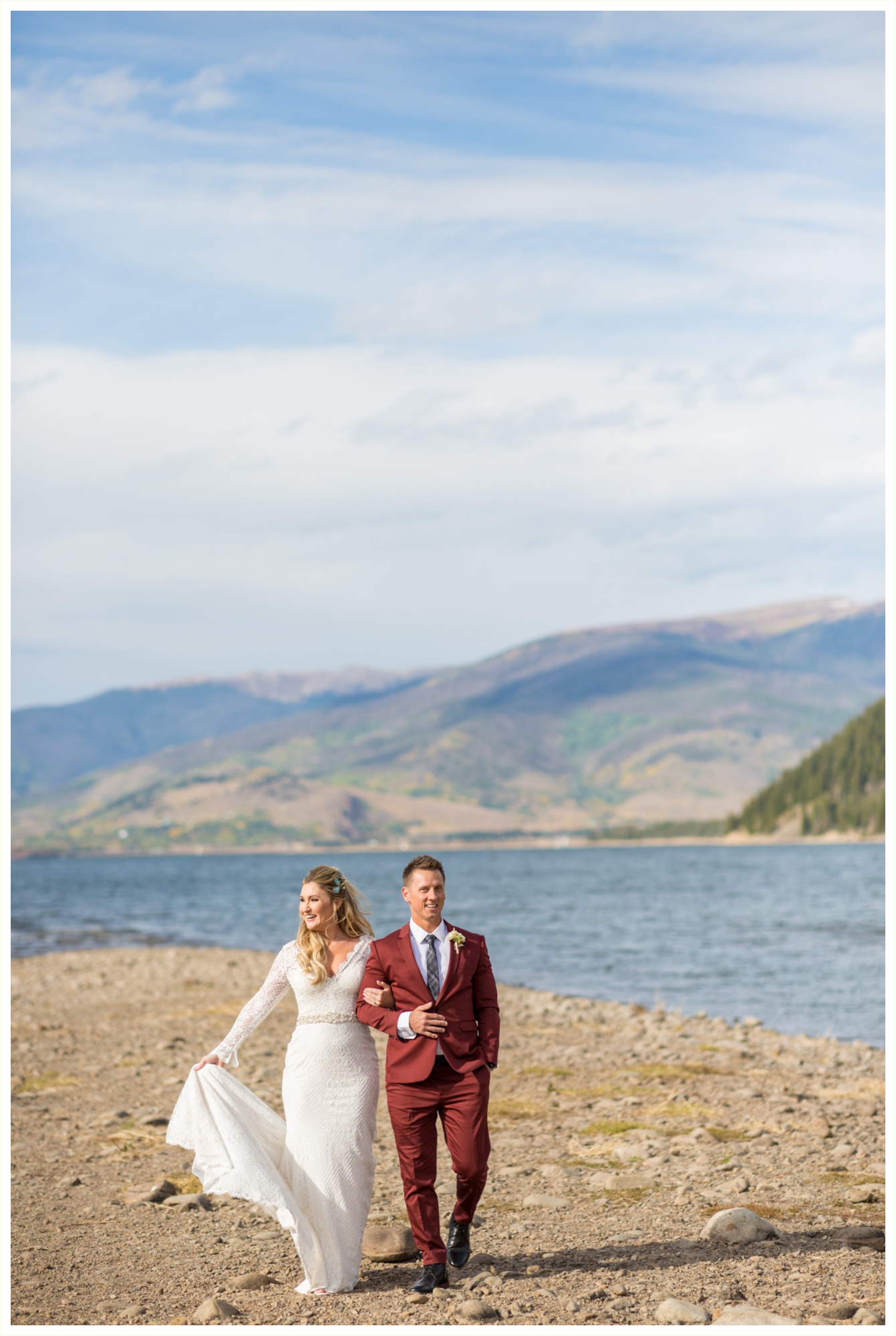 bride and groom photos at lake dillon before sapphire point elopement groom wears maroon suit bride has long sleeved dress walking candid photos beautiful rocky mountains
